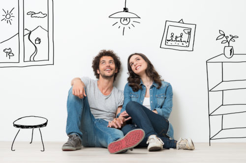 A man and woman sitting on the floor surrounded by animated representations of their dream home