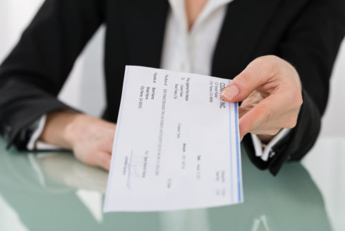 A bank teller handing a check to the person behind the camera.