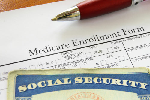A pen and social security card sit on top of a Medicare enrollment form.