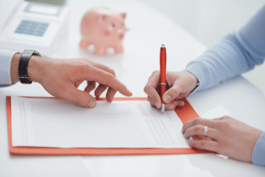 A woman signing an income tax loan form while a financial advisor points where to sign.