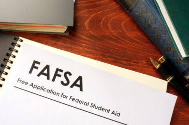 A document labeled "FAFSA" sits upon a table alongside a pen and some books.