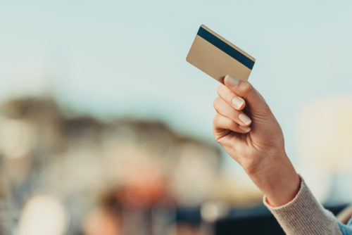 A hand holding up a credit card.