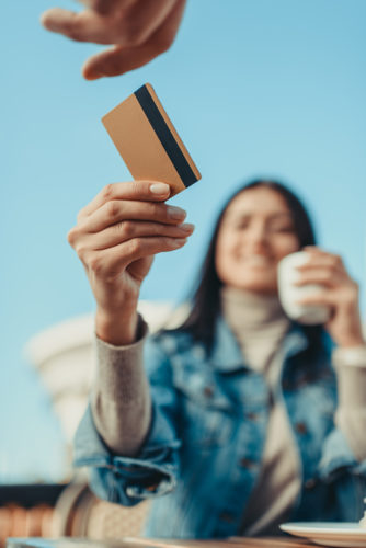 A woman handing a credit card to a person behind the camera.