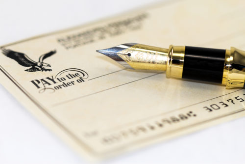 A fountain pen sits on top of a personal check.