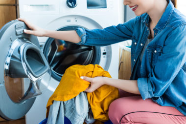 A woman doing pulling laundry out of the dryer.