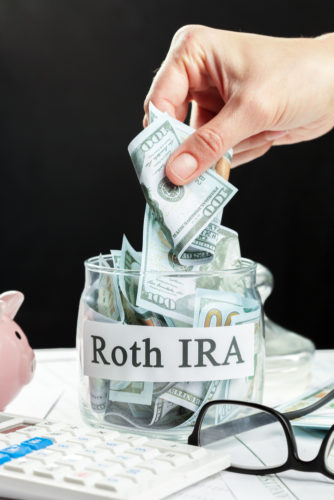 A person taking money out of a jar marked "Roth IRA."