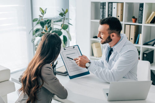 A doctor helping a woman fill out her health insurance claim.