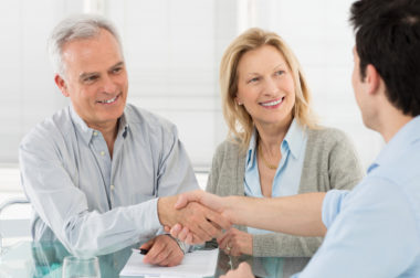An elderly couple shaking hands with their financial advisor.
