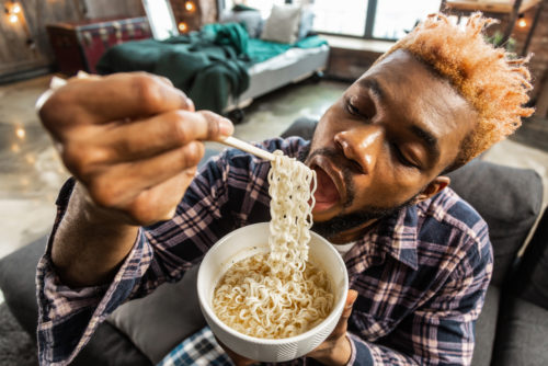 A millennial eating Ramen noodles while living at his parents' home.