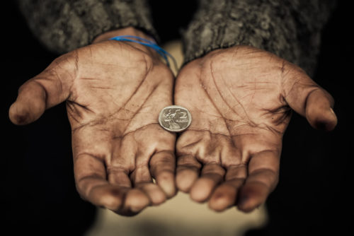 A poor man holds his hands out with one coin in it.