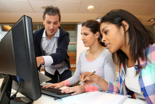 A trainer educating interns at a computer as part of their internship.