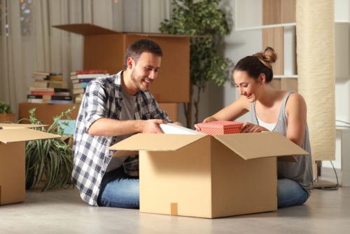 A student couple unpacking a box in their newly bought home.
