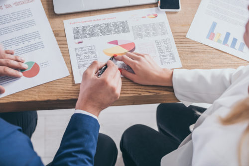 A woman sitting at a desk with an investment manager going over her investment portfolio.