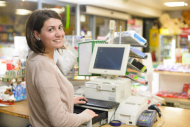 An employee at her job behind the computer at a retail store.