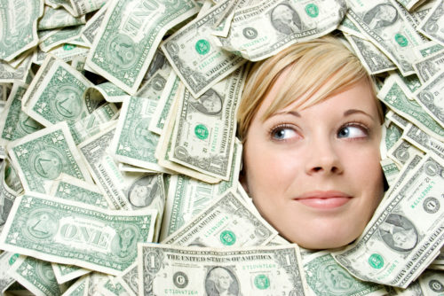 A woman's face peaking out from under a pile of cash.