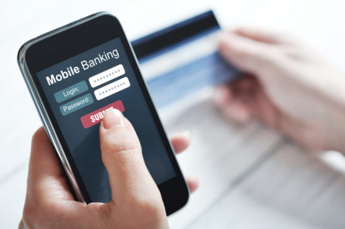 A person on their smartphone, logging into a screen that reads "mobile banking."