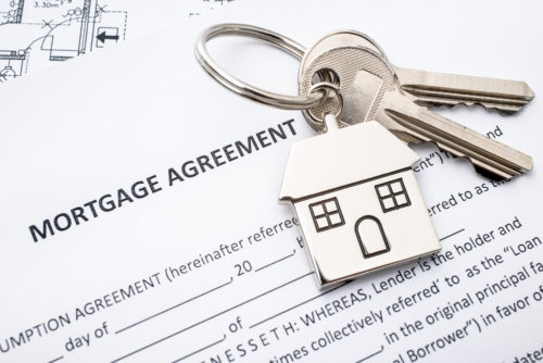 A set of keys sit on top of mortgage agreement.