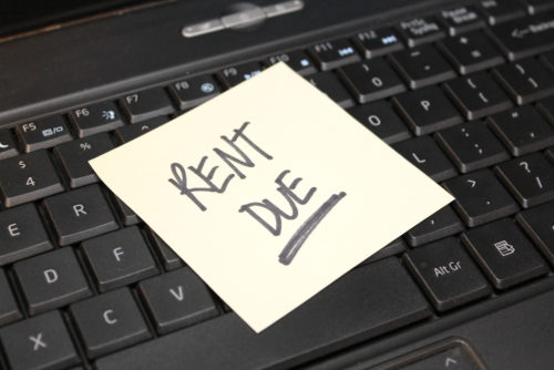A sticky note on a computer keyboard that reads "rent due."