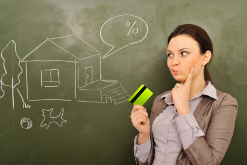 A woman in deep thought calculating a mortgage while a house and a percentage sign are drawn on a chalkboard behind her.