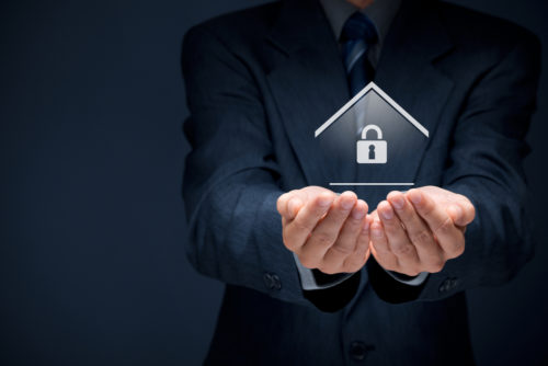 An insurance agent grasping a graphic of a home with a lock in the middle of the graphic.