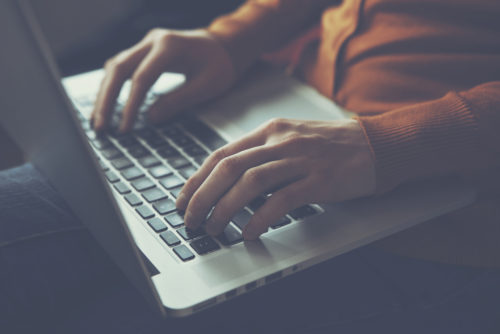 A closeup of hands typing a letter of interest on a laptop.