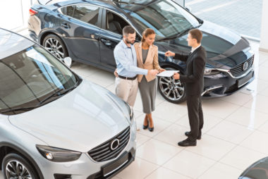 A couple speaking to a car salesman about buying a car.