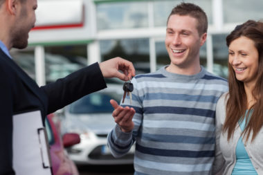 A young couple receives the keys to a new car.