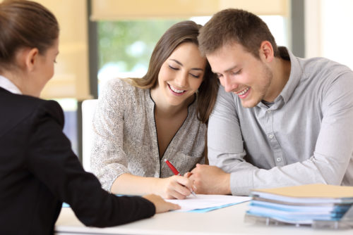 A couple signing a general warranty deed while closing on their property.