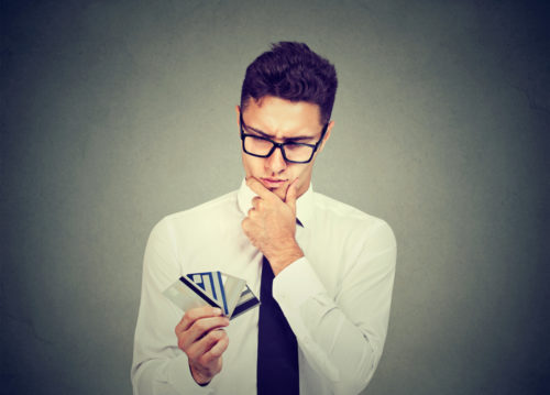 An inquisitive man analyzing his multiple reward credit cards.