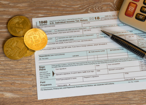 Bitcoins sit on top of a IRS report form.