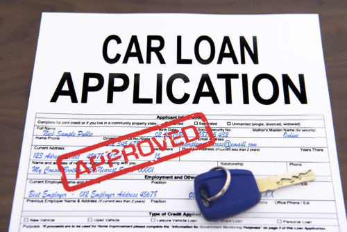 A car loan application with car keys sitting on top of it is rubber stamped approved.