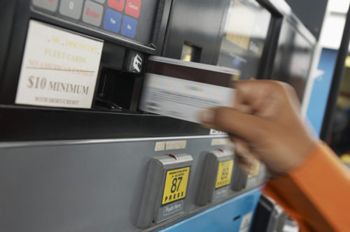 A credit card being inserted into a gas pump.