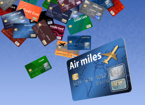 Various travel rewards cards falling out of the sky, one of them says "air miles."