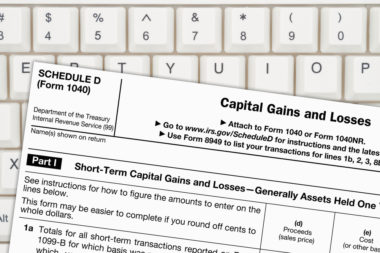 A capital gains and losses tax form sits on top of a computer keyboard.