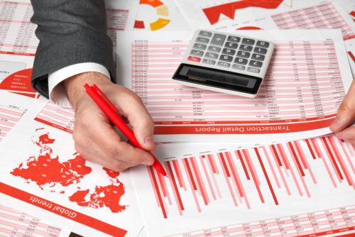 A business accountant calculating excise tax on a table riddled with tax figures and a calculator.