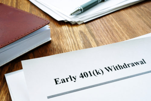 A document labeled "early 401(k) withdrawal" sits on a desk with a notebook, pen, and other various papers.