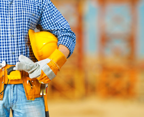 A construction worker holding his hardhat on his arm.