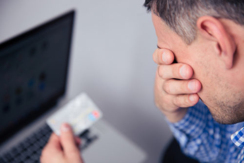 An upset man, who has lost his rewards, holding a credit card.