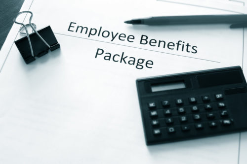 A calculator, pen, and paperclip sit on top of a document labeled "employee benefits package."