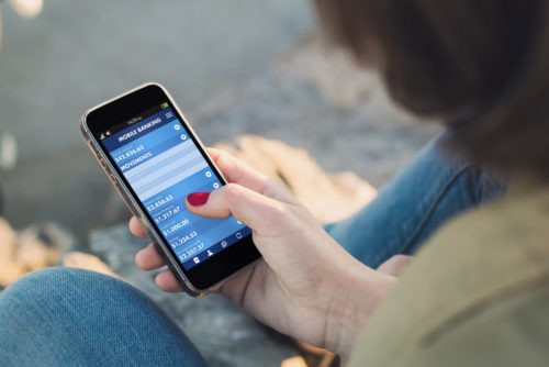 A woman holding a smartphone that displays a personal finance app.