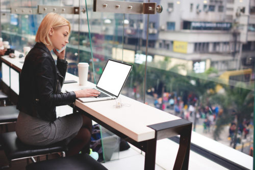 An independent contractor works on her laptop in a coffee shop.