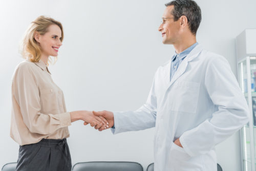 An internist shaking hands and greeting a patient.