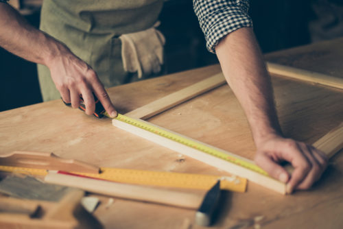 A man measuring out a piece of wood for a DIY project.