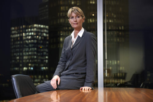A CEO leaning against her conference desk.