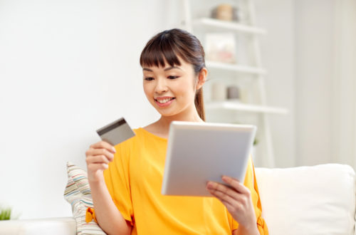 A woman with her credit card and tablet, waiting for preapproval.