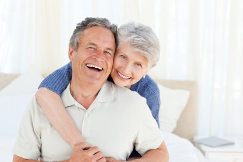 A retired couple hugging and smiling.