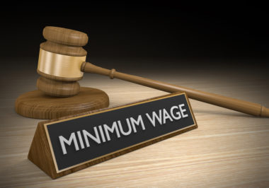 A gavel sits next to a placard that reads "minimum wage."