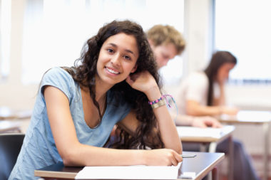 A woman in her 20s smiling in a classroom.