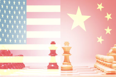 Chess figures on a chessboard with both the American and Chinese flag superimposed over them, symbolizing a trade war between the two countries.