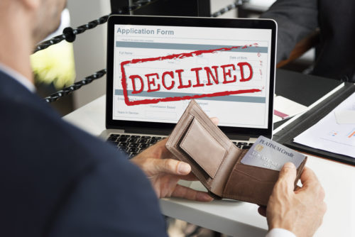 A man's laptop screen reads "declined" after he uses his credit card to make an online purchase.